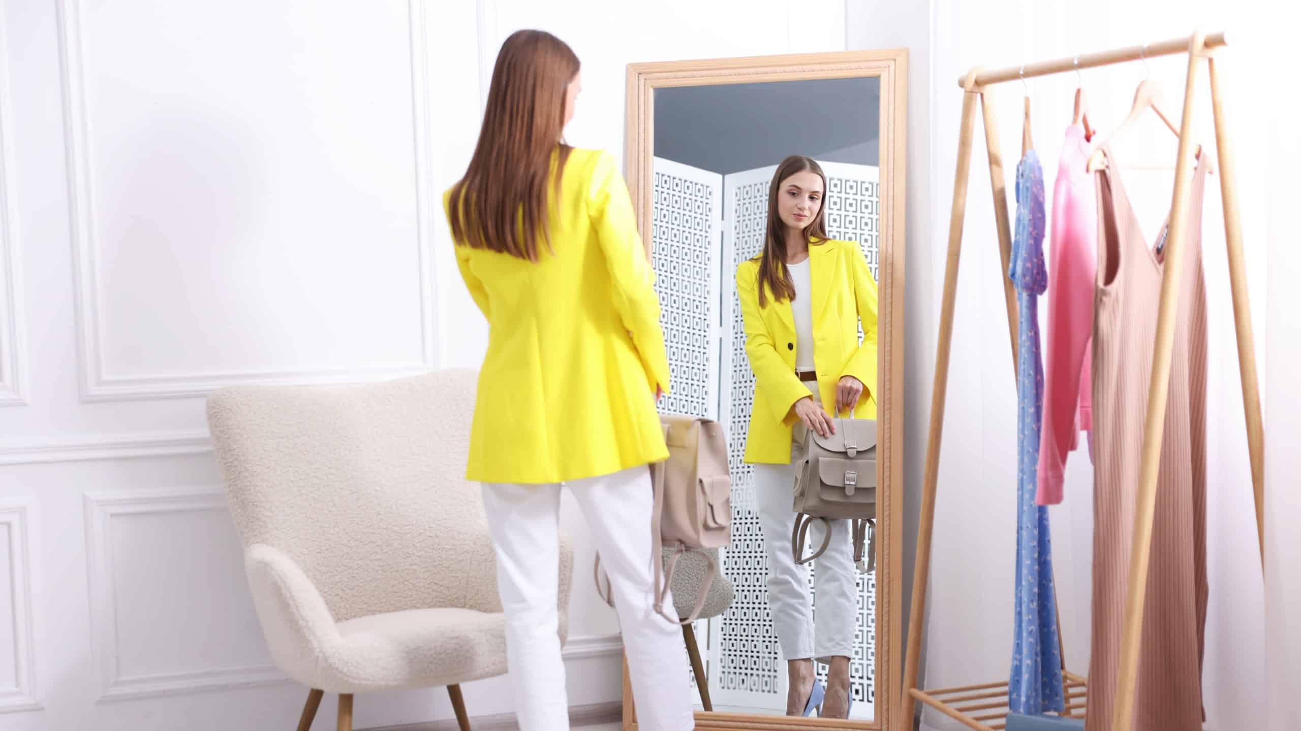 Getting ready. Young woman trying on clothes near mirror at home