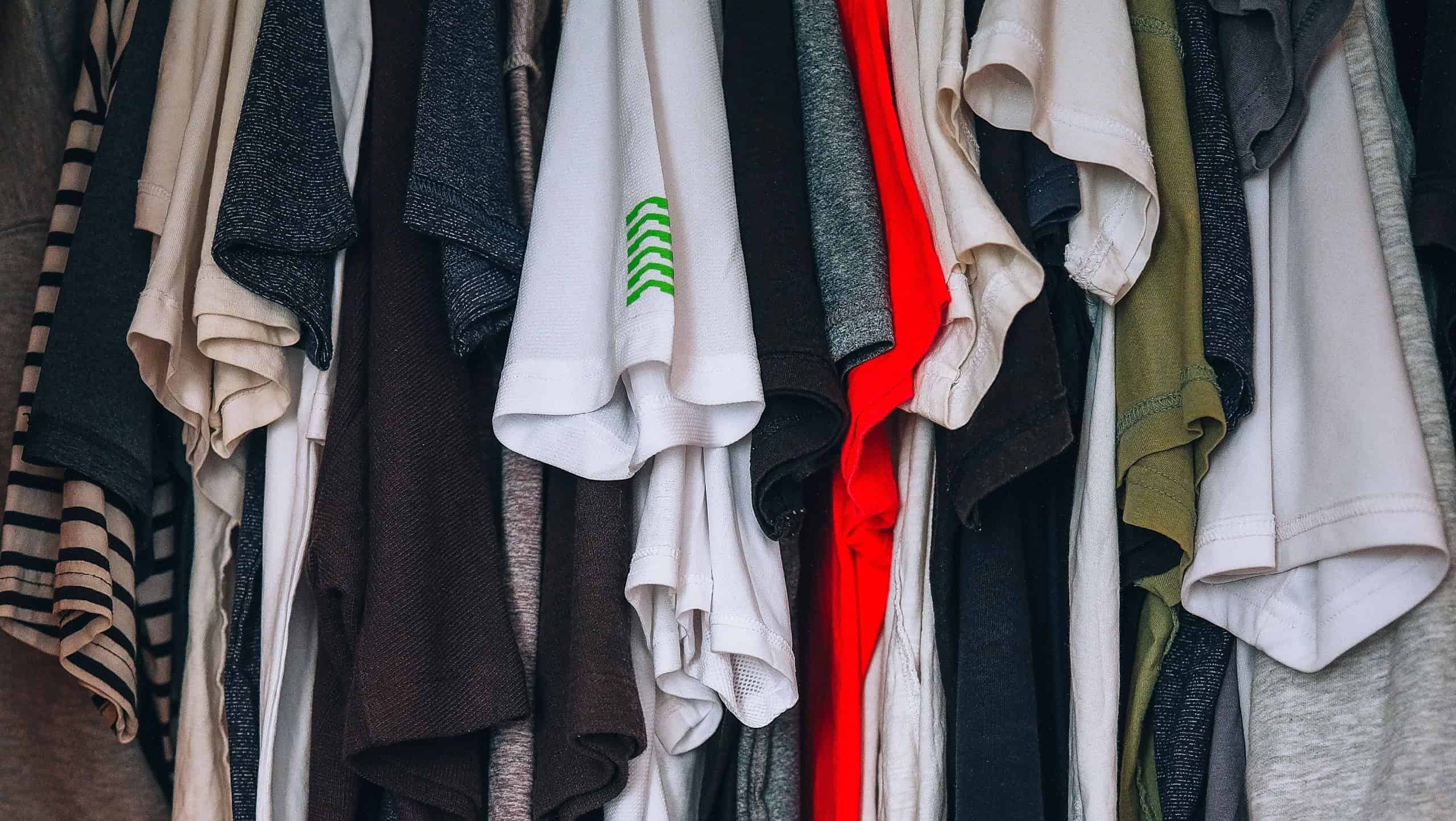 Many colorful clothes hanging on hanger. Charity donation, thrift store, garage sale or full closet at home.