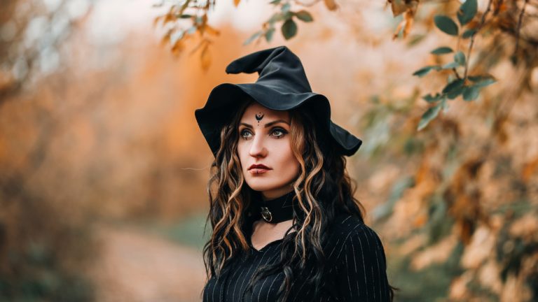 Portrait of girl in witch costume on forest background.