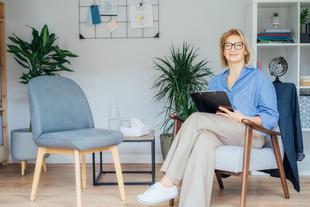 Professional Psychotherapy. Successful female Psychologist Smiling To Camera Sitting On armchair In Office. Mature 50s middle-age professional portrait of teacher, coach, mentor, therapist, counselor