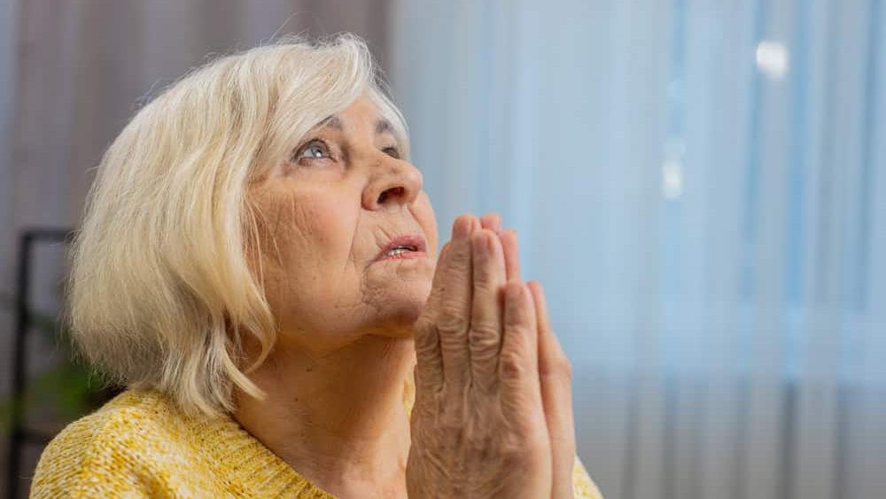 Please, God help. Close-up of worried senior woman praying for heath sincerely with folded arms, looking upward making wish, asking hopeful imploring expression begging apology. Elderly grandmother