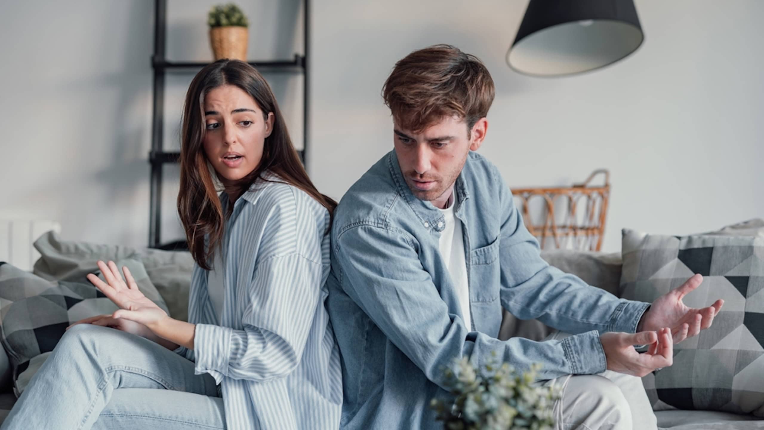 Beautiful lady is depressed, sitting on the couch talking to man, having a dispute with husband or girlfriend, looking desperate and hopeless, having unresolved problem or question