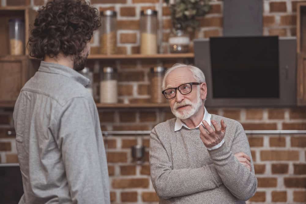 adult son and senior father talking at kitchen home