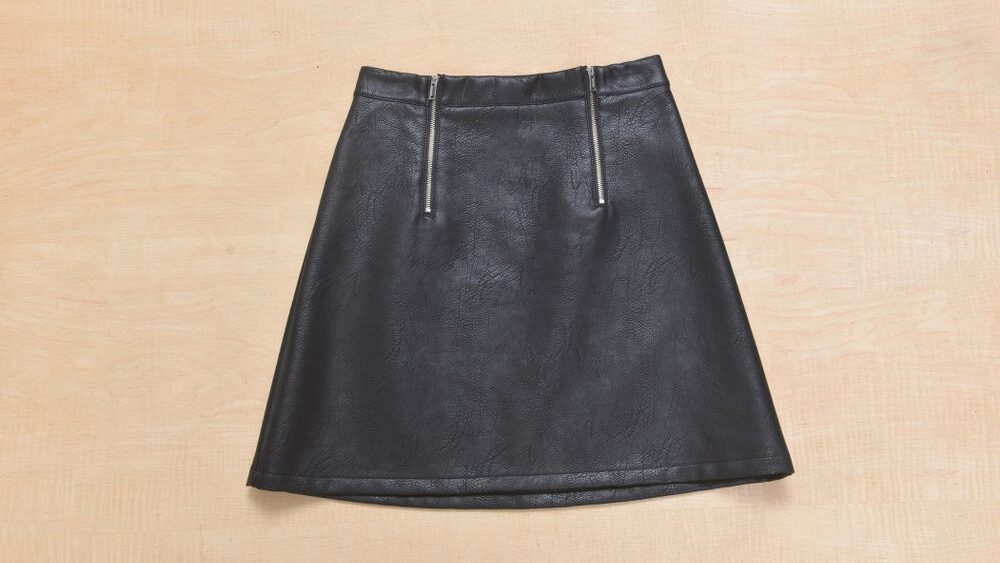 Black leather mini skirt isolated over wooden background