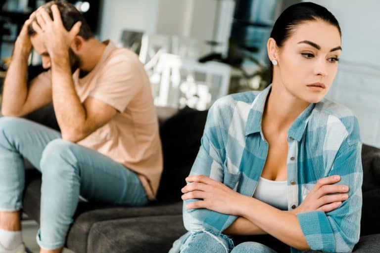 upset couple sitting on couch after arguing at home