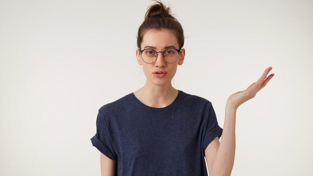 Daughter hates when parents scolding. Bothered and annoyed european female student keps one hand up standing over white background, being bored and fed up of nonsense talks