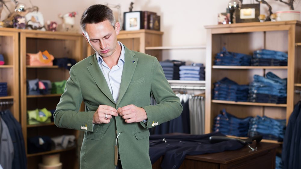 Young man customer choosing fashion suit in men’s store