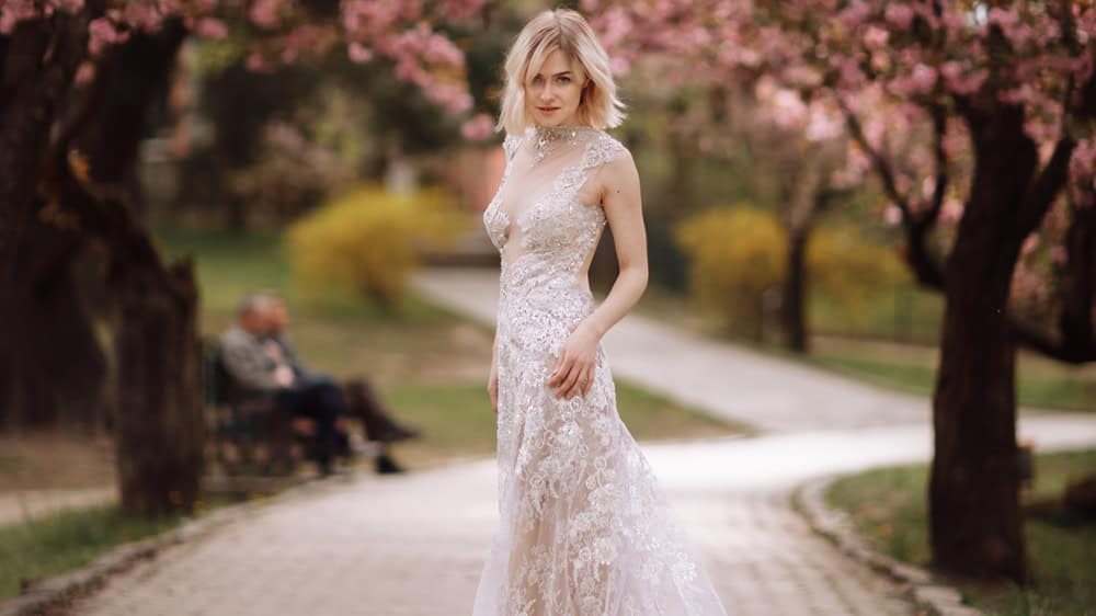 woman's day. beautiful young woman in luxury long dress near blossoming of sakura. stylish girl near blossoming sakura flowers on background in the spring park. Harmony with nature concept.