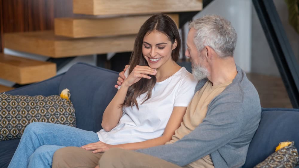 Family. An aged man and young woman sitting together on a sofa