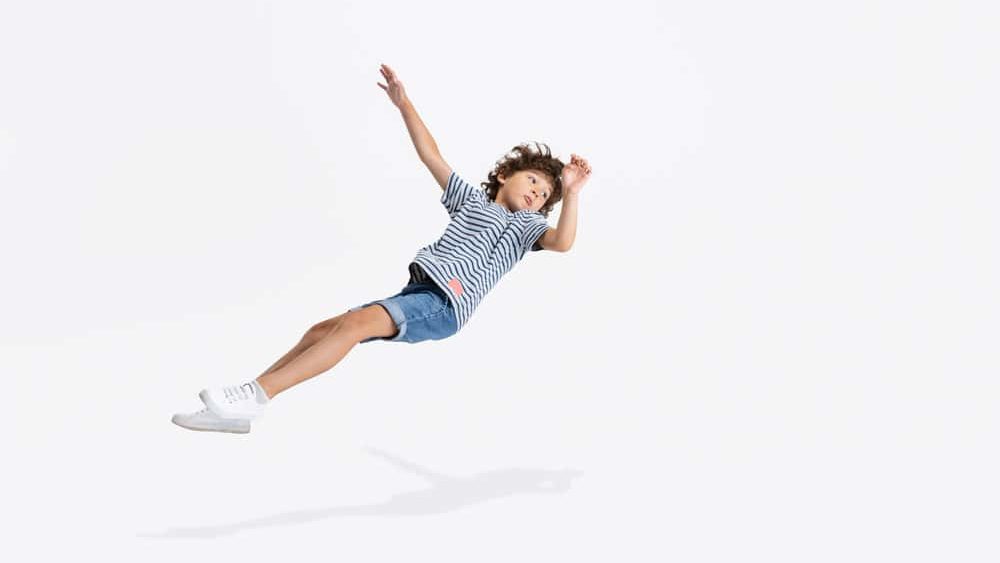 Levitation. One Caucasian preschool boy playing, falling to floor isolated over white studio background. Copyspace for ad. Happy childhood, education, emotions, facial expression concept. Having fun