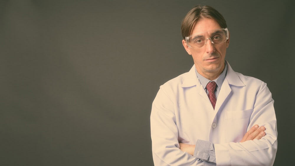 Studio shot of mature handsome Italian man doctor wearing protective glasses against gray background