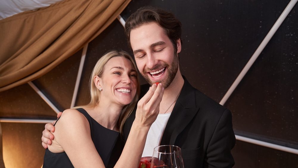 Girlfriend bringing strawberry to mouth of her boyfriend