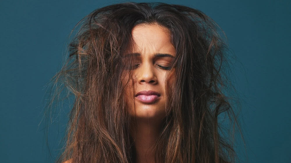Pain you hold makes you worth your weight in gold. Studio shot of a beautiful young woman with messy hair posing against a blue background.