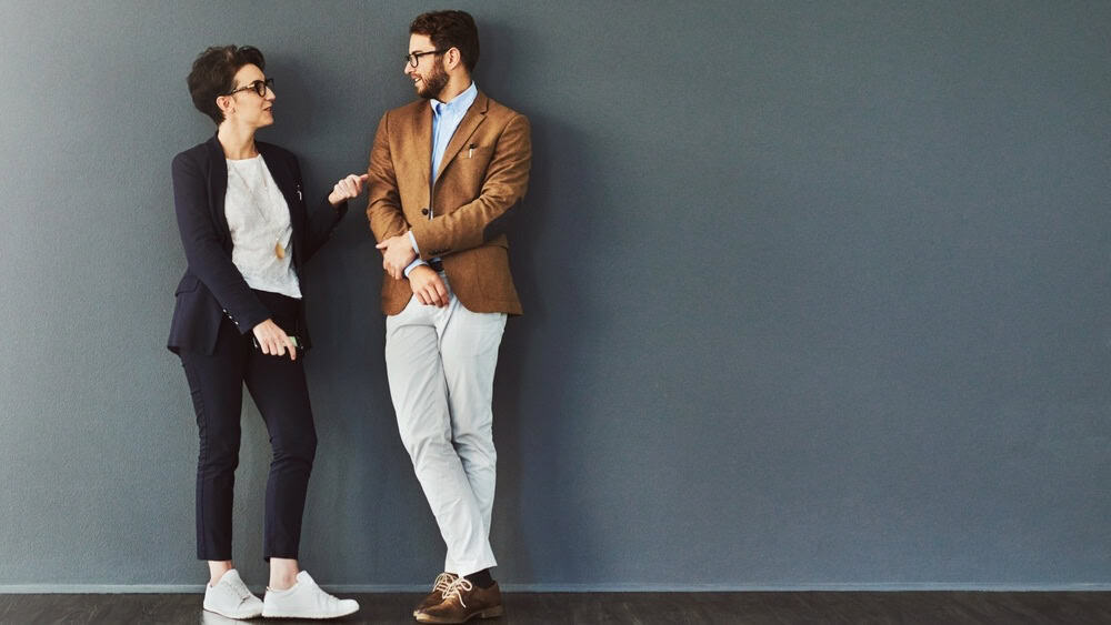 You gain so much from mingling. Shot of two designers having a conversation while leaning against a wall.