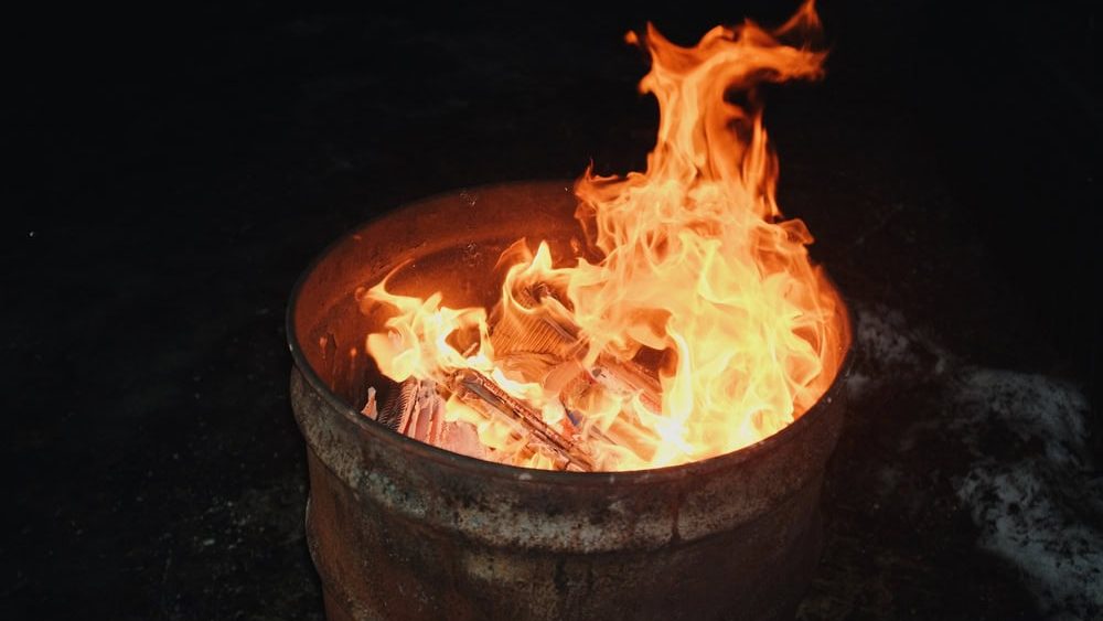 fire burning inside a metal barrel at night