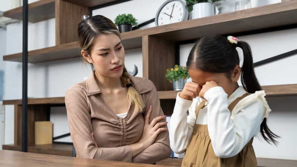 Angry mother scolding little daughter at home, mom berating crying child, Problems between kid and parent, copy space