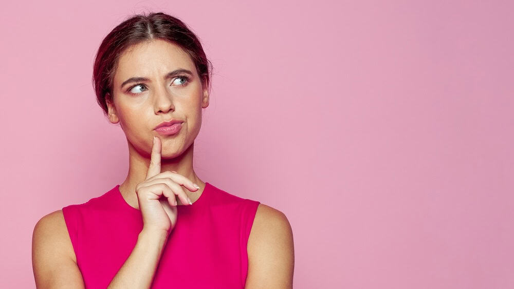 Attractive young woman thinking on pink background. Idea and brainstorming concept
