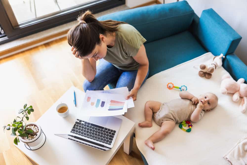 Shot of a busy young mother looking stressed while working at home while caring for her adorable baby.