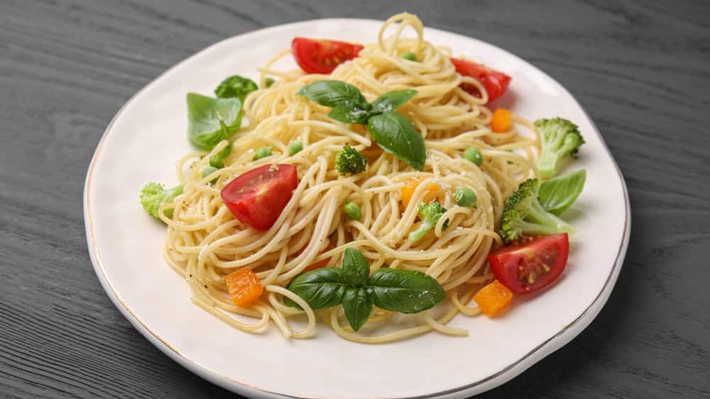 Delicious pasta primavera with tomatoes, basil and broccoli on grey table, closeup