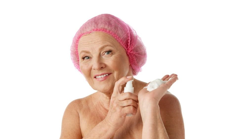 Beauty routine. Beautiful senior woman applying face cleansing foam against white studio background. Makeup removal. Concept of natural beauty, aging process, elderly beauty, cosmetology, skincare
