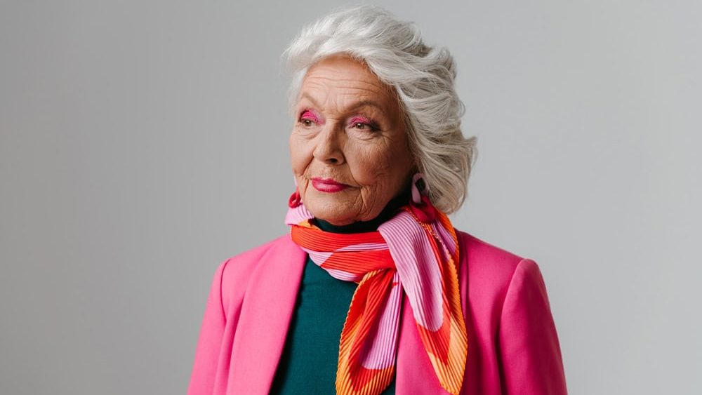 Elegant elderly woman with make-up wearing fashionable clothing and radiating self-love