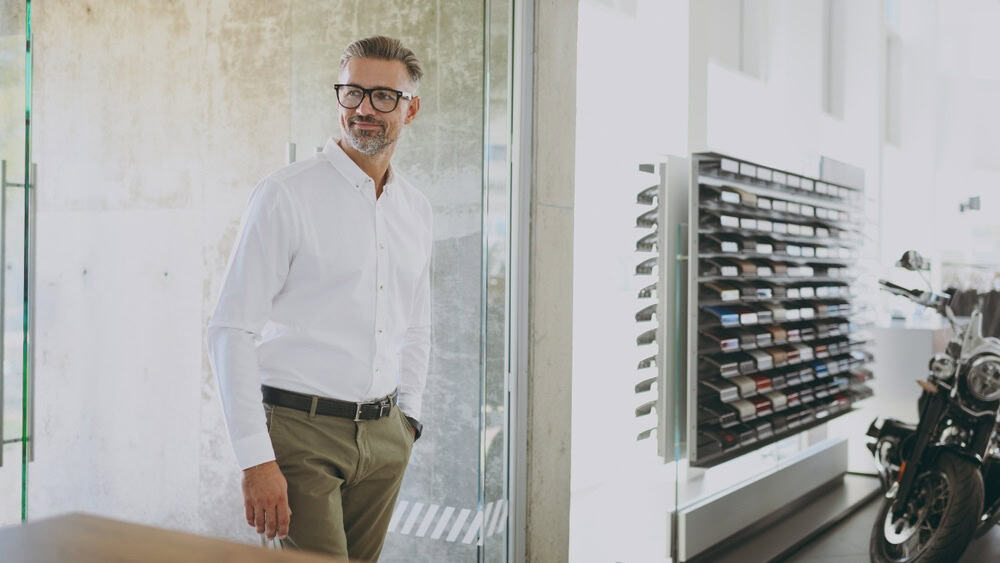 Confident smiling cheerful adult man customer male buyer client wear shirt enter office want to buy choose new auto automobile in car showroom vehicle salon dealership store motor show. Sales concept