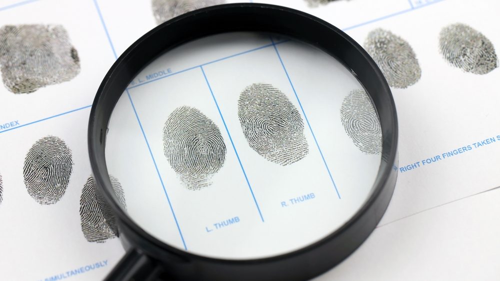 Fingerprints card police form on A4 tablet lies on office table with pen and magnifying glass close up