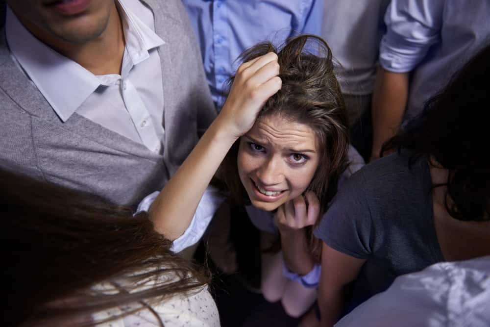 Woman, people and social anxiety in stress with fear, worried and panic with nervous, thinking and phobia. From above, female person and scared as introvert in conference with group and insecure