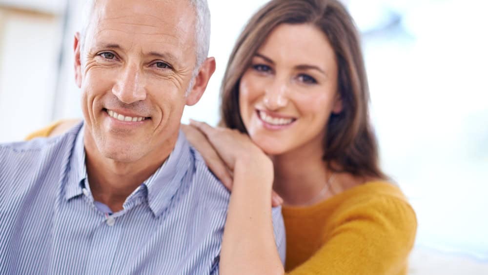 Couple, age difference and relax in portrait, love with unique relationship and support for trust at home. Senior man, young woman in marriage, commitment and loyalty with partner and pride together