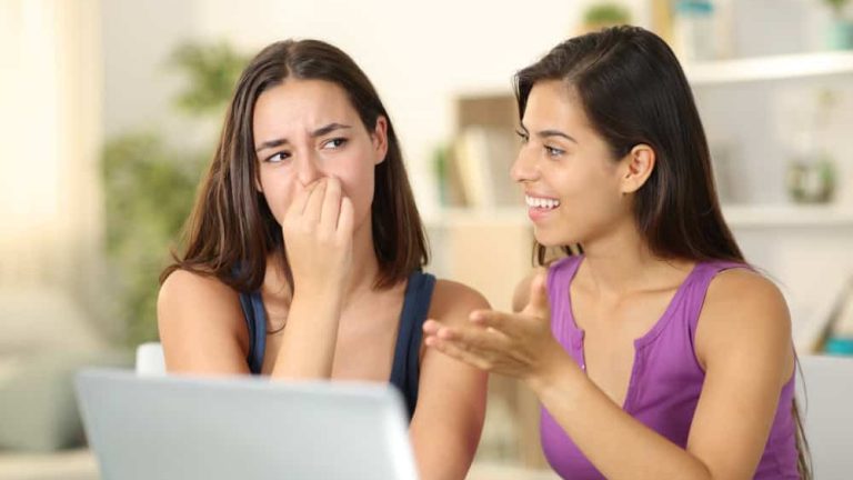 Woman with bad breath talking to a disgusted friend at home