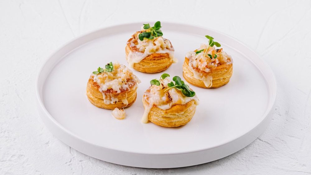 Three delicious shrimp vol-au-vents garnished with herbs on a white plate, perfect for elegant appetizers