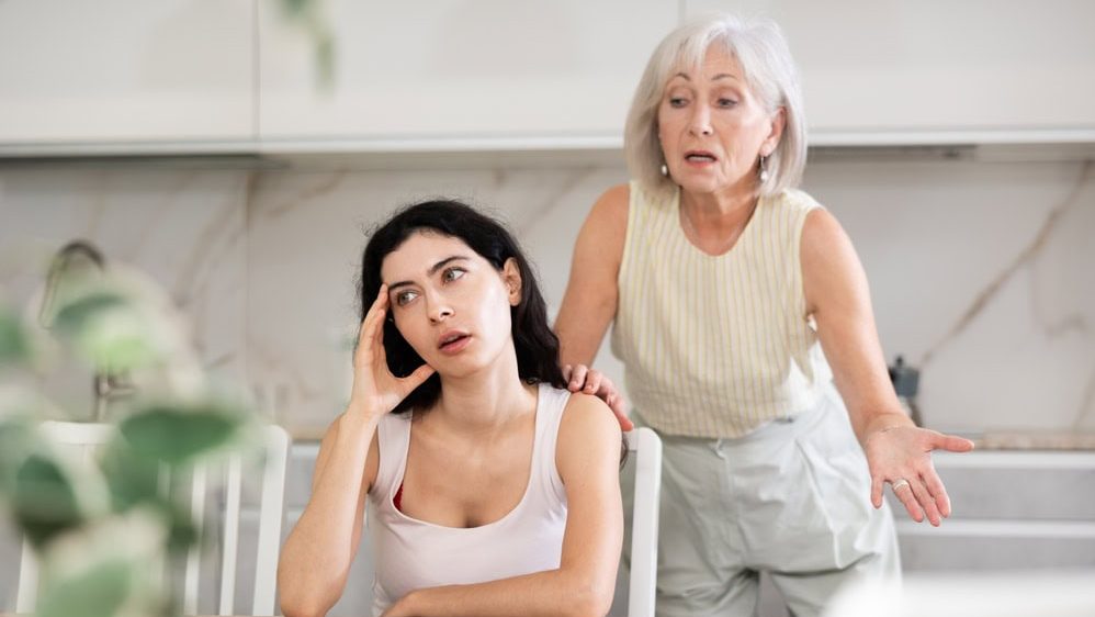 Elderly woman during family quarrel with young woman in kitchen at home