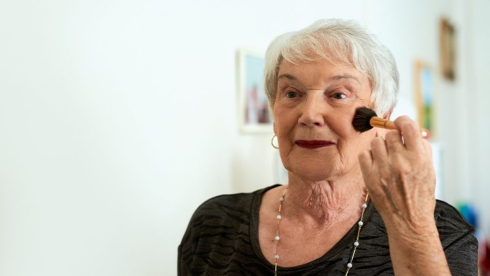 Home, makeup and senior woman with brush for beauty, wellness and confidence for facial transformation. Elderly lady, happy and apply powder in bathroom with blush for cosmetic results and skin glow