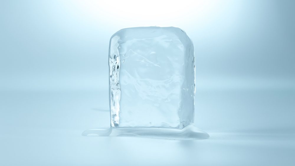 Cube of clear ice on light blue background