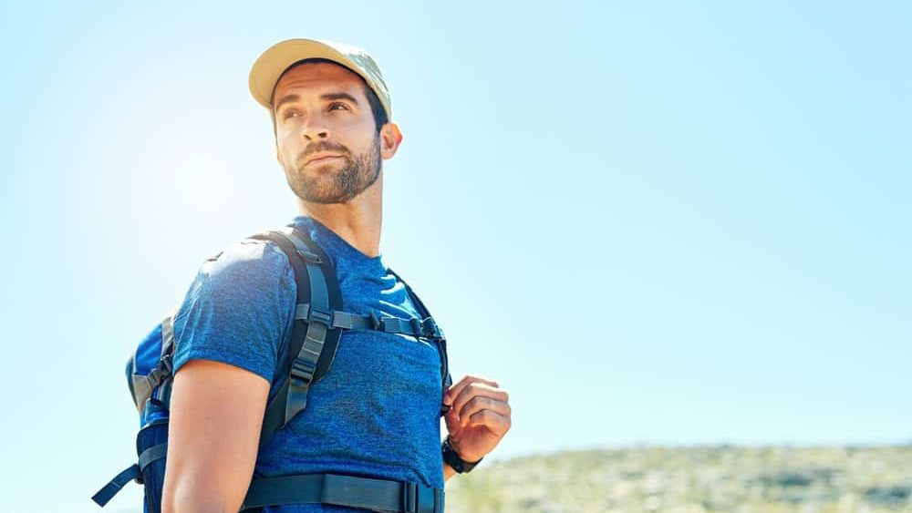 Man, backpack and hiking or thinking outdoor for fitness adventure, cardio or walking to explore the environment. Hiker, person and trekking for body wellness, exercise or nature with mockup space