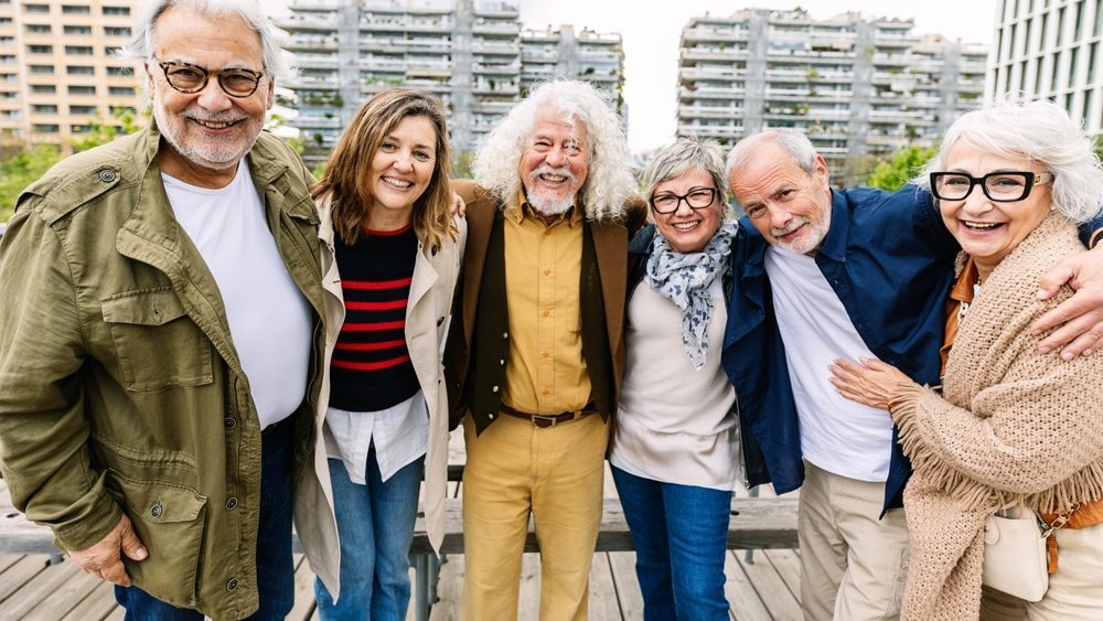 Portrait of happy senior group of people smiling at camera standing together at city street. Baby boomers and elderly friendship concept