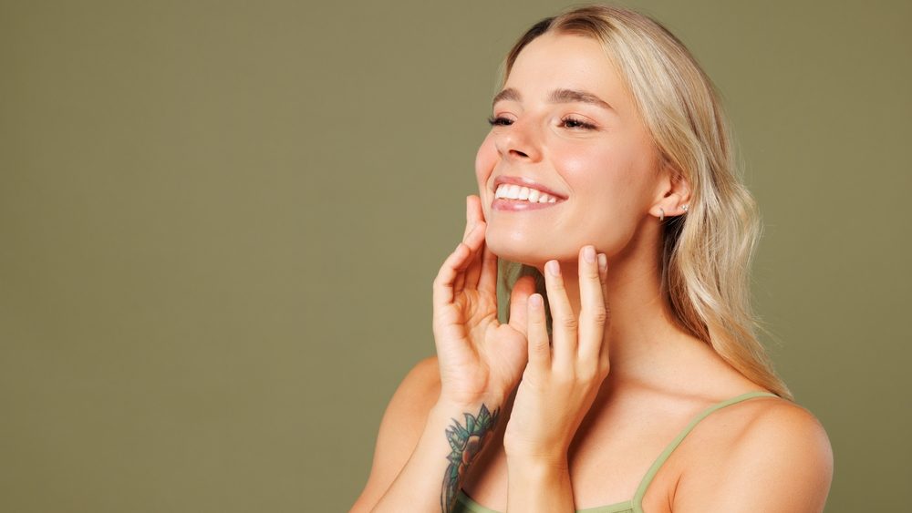 Close up side view young lady woman with slim skinny body perfect skin wear top bra lingerie stand touch face look aside on area isolated on plain pastel green background. Lifestyle diet fit concept