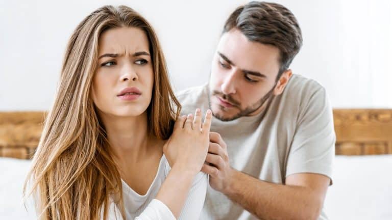 Relationship problems and apologies. Husband calms his wife, upset woman rejects man on bed, free space
