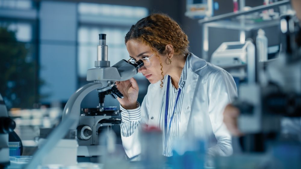 Portrait of a Multiethnic Student Working on a Research Project in College. Medical Research Scientist Looking at Biological Samples Under a Microscope in an Applied Science Laboratory