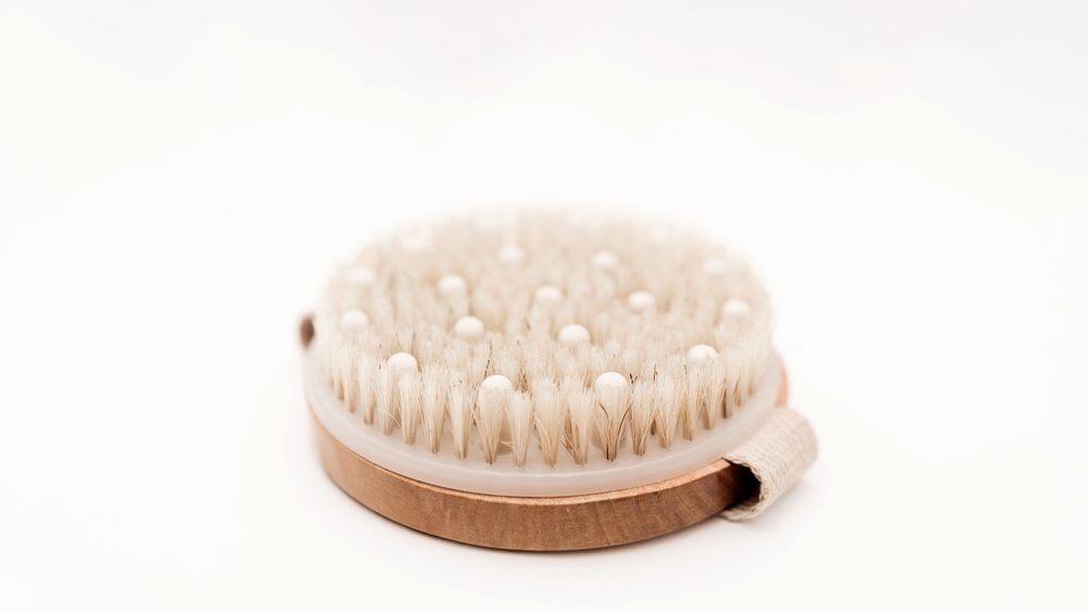Round wooden dry massage brush with natural bristles and massage beads for body care, cellulite treatment, and skin exfoliation