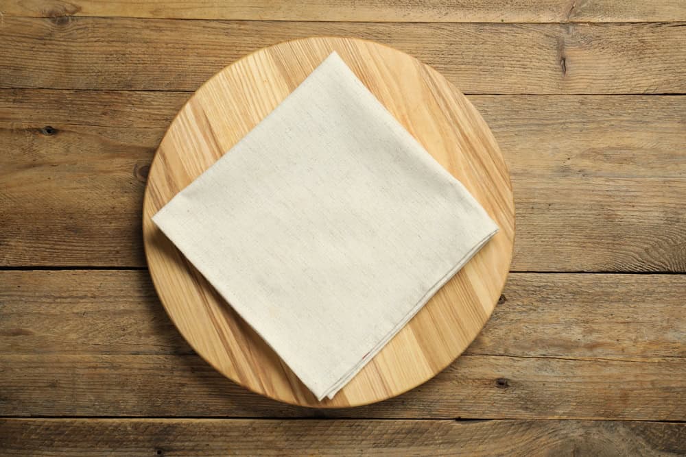 Light napkin and board on wooden table, top view