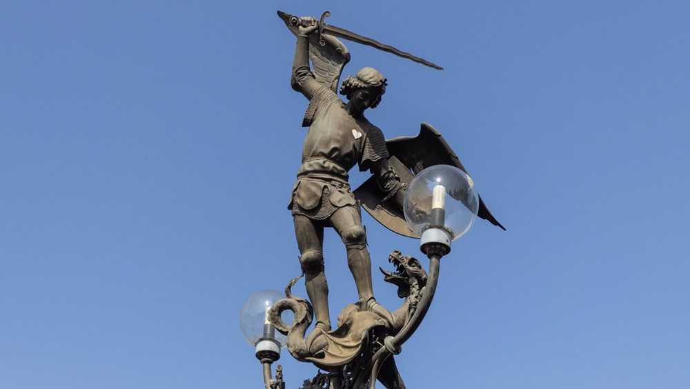 Ghent, Belgium - May 19, 2023: Lantern with bronze sculpture of Archangel Michael (Saint Michael) standing on dragon. It is located on famous arched Saint Michael's Bridge