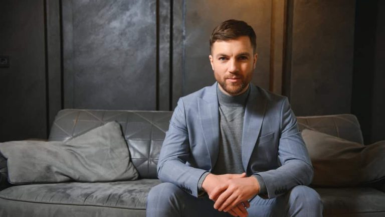 Respectable handsome man in elegant suit in apartments with classical luxurious interior. Men's beauty, fashion.
