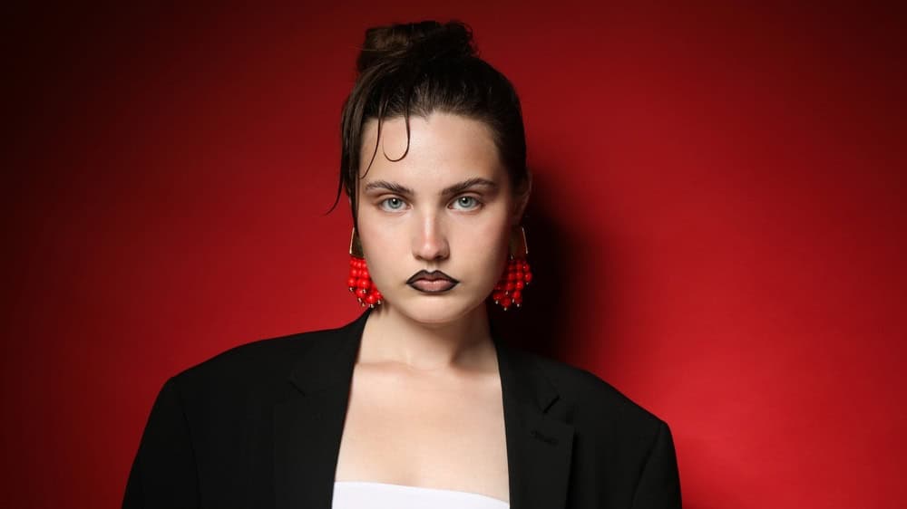 Portrait, hair and woman in studio with edgy style, funky and 80s look on pink background. Confident, cool or retro for female person with stylish, jewelry and fashion for trendy aesthetic with space