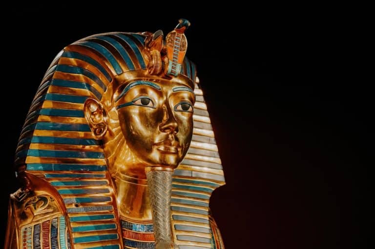 Golden funerary mask of an Egyptian pharaoh with blue and gold stripes.