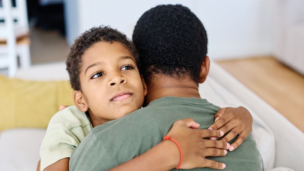 Portrait of son hugging his father, together at home. Son caring for his father, putting hand on his shoulder, comforting and consoling him. Family love, bonding, care and confidence