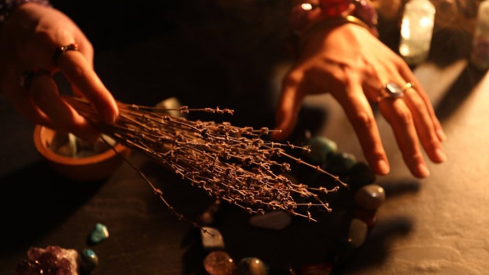 Woman doing ritual with healing stones at dark table, closeup