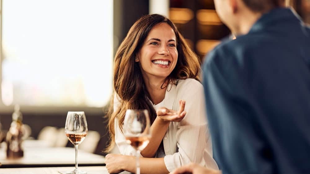 Happy woman engaging in lively conversation at a cozy social setting with wine.