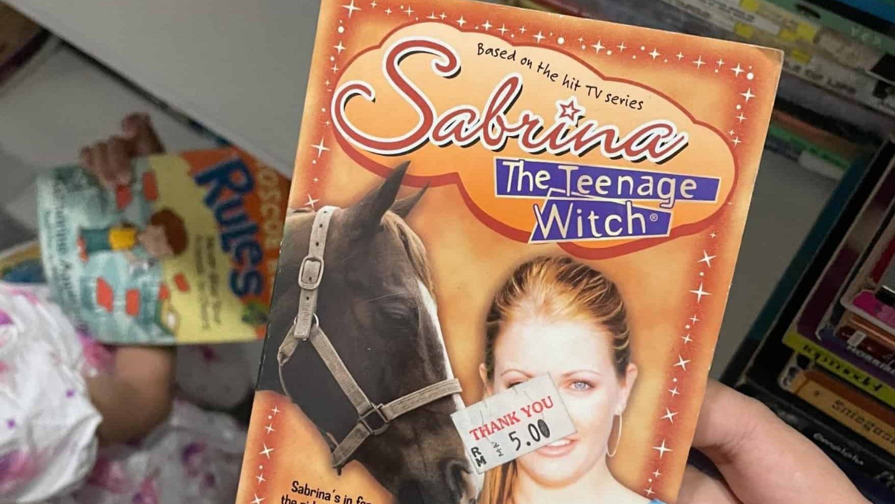 Person holds Sabrina Teenage Witch book in store.