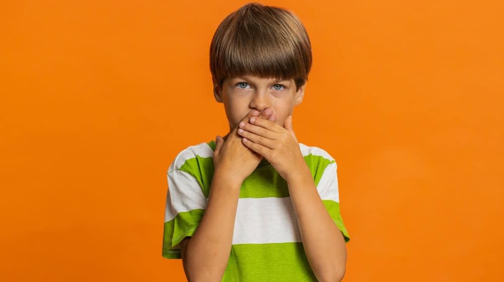 I will not say anything. Frightened strict young preteen child boy kid closing mouth with hands, looking intimidated scared at camera gestures no, refusing to tell terrible secret unbelievable truth.